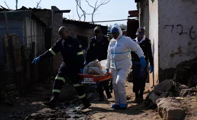 Police officers carry the body of a person on a stretcher after a mass shooting at an informal settlement in the Cleveland suburb of Johannesburg, South Africa, Wednesday, June 10, 2026. (AP Photo/Themba Hadebe)