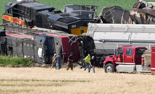 Workers and first responders walk past damage after a train derailed on Wednesday, June 3, 2026, near Victor, Iowa. (AP Photo/Charlie Neibergall)
