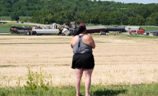 A woman records on a phone after a train derailed on Wednesday, June 3, 2026, near Victor, Iowa. (AP Photo/Charlie Neibergall)