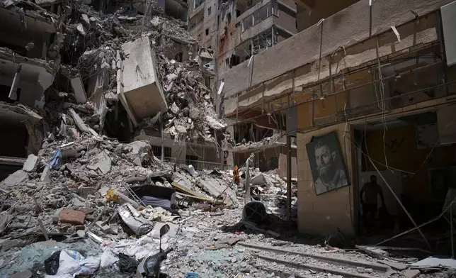 Barber Wissam Srour, 41, right, searches for belongings in the rubble of his barbershop, damaged in an Israeli strike, in the southern port city of Tyre, Lebanon, Friday, June 19, 2026. (AP Photo/Hassan Ammar)