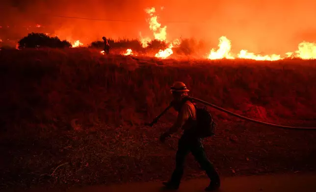FILE - A firefighter monitors flames caused by the Hughes Fire along Castaic Lake in Castaic, Calif., Jan. 22, 2025. (AP Photo/Jae C. Hong, File)