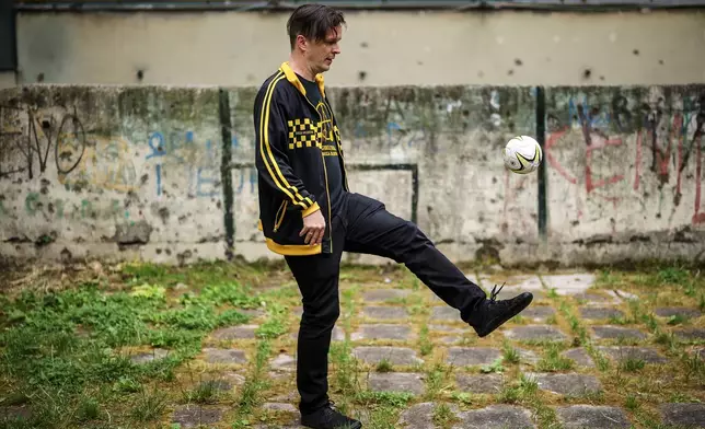 Vedran Mujagic, a member of Bosnian band Dubioza kolektiv, plays with a ball at a soccer playground where the video for the song "I Am From Bosnia, Take Me to America" was filmed, in Sarajevo, Bosnia, Thursday, June 11, 2026. (AP Photo/Armin Durgut)