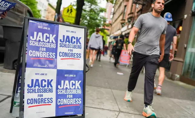 A man walks past a campaign sign for Democratic Congressional Candidate Jack Schlossberg during New York's primary election on Tuesday, June 23, 2026, in New York. (AP Photo/Ryan Murphy)