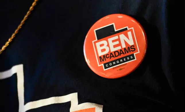 A supporter wears a button for candidate Ben McAdams speaks during a watch party for Utah's primary election on Tuesday, June 23, 2026, in Salt Lake City. (AP Photo/Alex Goodlett)