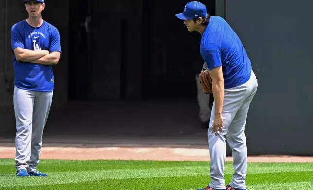Los Angeles Dodgers two-way player Shohei Ohtani, from Japan, touches his knee before a baseball game against the Chicago White Sox, Saturday, June 13, 2026, in Chicago. (AP Photo/Matt Marton)