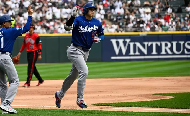 Los Angeles Dodgers' Shohei Ohtani, right, of Japan, gestures after he hit a home run during the first inning of a baseball game against the Chicago White Sox, Saturday, June 13, 2026, in Chicago. (AP Photo/Matt Marton)
