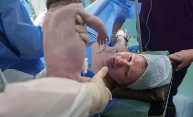 A doctor shows Olha Karpenko her newborn daughter, Diana, for the first time after her birth by cesarean section at the regional perinatal center of Zaporizhzhia, Ukraine, Wednesday, May 6, 2026. (AP Photo/Evgeniy Maloletka)