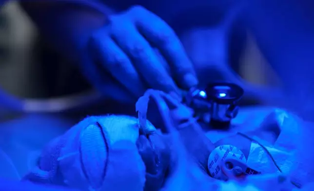 Dr. Andrii Lobanov listens to a premature baby's heartbeat with a stethoscope inside a temperature-controlled incubator at the regional perinatal center of Zaporizhzhia, Ukraine, Wednesday, May 6, 2026. (AP Photo/Evgeniy Maloletka)