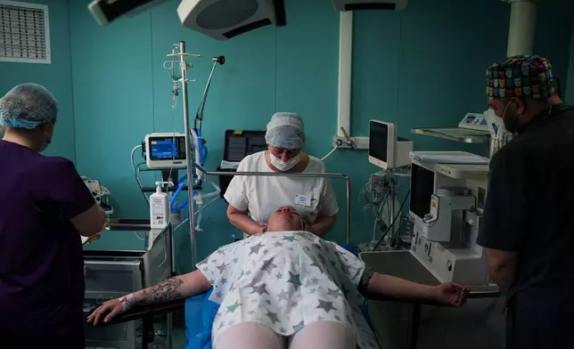 A medic calms Olha Karpenko before a cesarean section at the regional perinatal center of Zaporizhzhia, Ukraine, Wednesday, May 6, 2026. (AP Photo/Evgeniy Maloletka)
