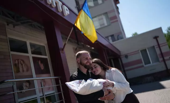 Mariia Skladan, right, her husband Vladyslav and their daughter Elina pose for a photo after mother and baby left the regional perinatal center of Zaporizhzhia, Ukraine, Wednesday, May 6, 2026. (AP Photo/Evgeniy Maloletka)