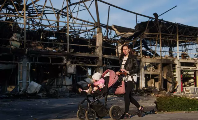 A woman pushes her baby in a stroller past a car workshop destroyed in a Russian attack in Zaporizhzhia, Ukraine, Wednesday, May 6, 2026. (AP Photo/Evgeniy Maloletka)