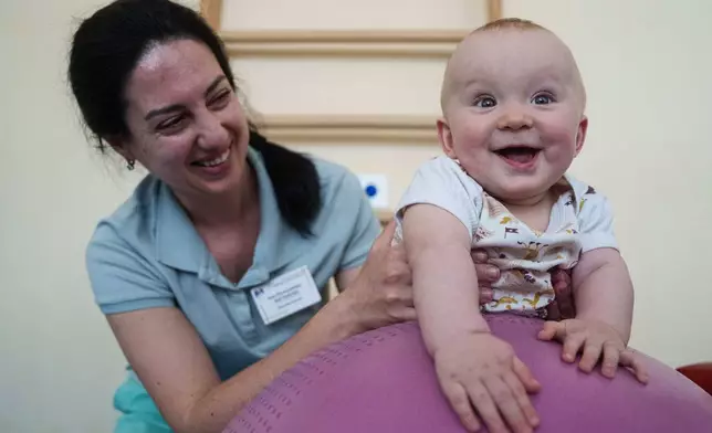 A medic does exercises with a 1-year-old child during a therapy session at the children's regional hospital in Zaporizhzhia, Ukraine, Thursday, May 7, 2026. (AP Photo/Evgeniy Maloletka)