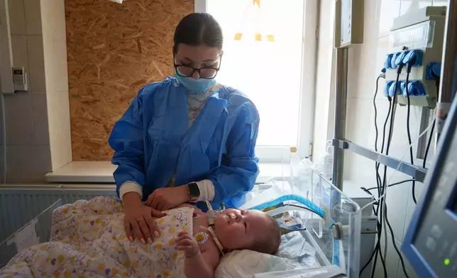 Dasha Kosmin touches her son Mark at the ICU department of the children's regional hospital in Zaporizhzhia, Ukraine, Thursday, May 7, 2026. (AP Photo/Evgeniy Maloletka)