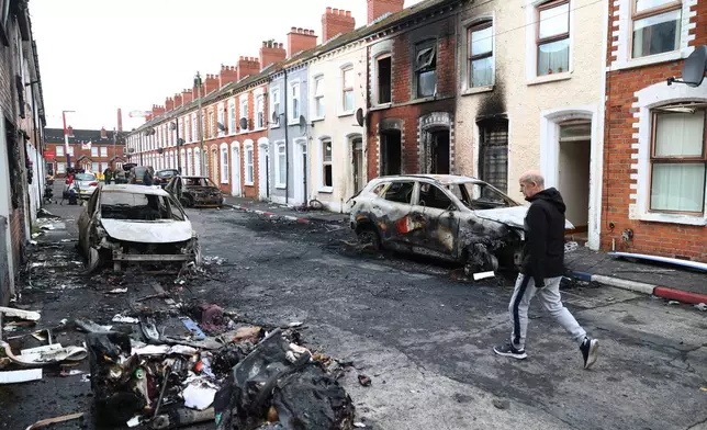 A man walks down a street after rioting broke out late Tuesday, in east Belfast, Northern Ireland, Wednesday, June 10, 2026, following a stabbing incident. (AP Photo/Peter Morrison)