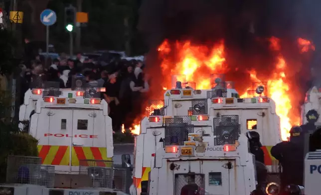 Police attempt to disperse protesters as a fire burns near Newtownabbey, in Belfast, Northern Ireland, Wednesday, June 10, 2026, following a stabbing incident on Monday night. (PA via AP)