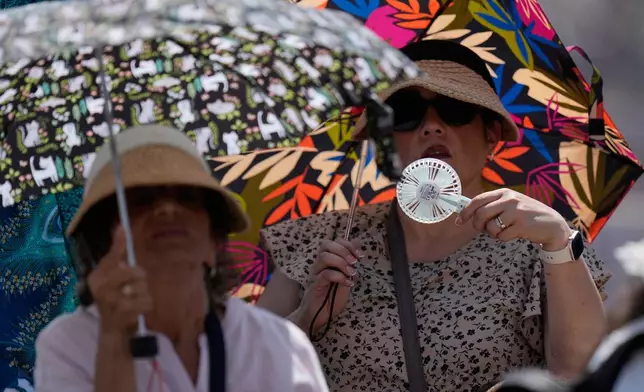 Faithful shelter from the hot sun as Pope Leo's XIV arrives for his weekly general audience in St. Peter's Square at The Vatican, Wednesday, June 24, 2026. (AP Photo/Alessandra Tarantino)