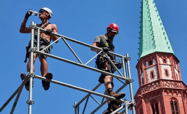 A worker drinks water as he sets up a stage for the upcoming Ironman triathlon, Frankfurt, Germany, Thursday, June 25, 2026. (AP Photo/Michael Probst)