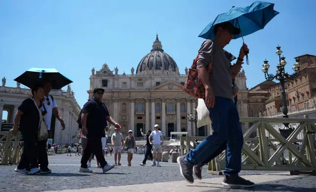 People shade from the sun under umbrellas as they walk through St. Peter's Square at the Vatican, Thursday, June 25, 2026. (AP Photo/Andrew Medichini)