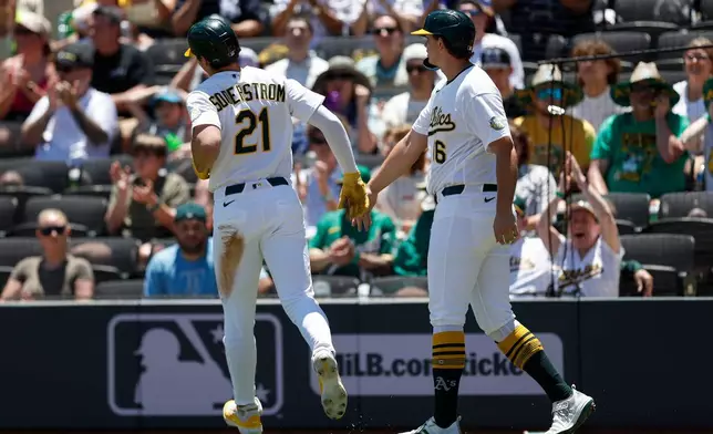 Athletics' Tyler Soderstrom (21) is greeted by designated hitter Nick Kurt, right after they scored on a single hit by Carlos Cortes during the first inning of a baseball game against the Colorado Rockies, Sunday, June 14, 2026, in Las Vegas. (AP Photo/Caroline Brehman)