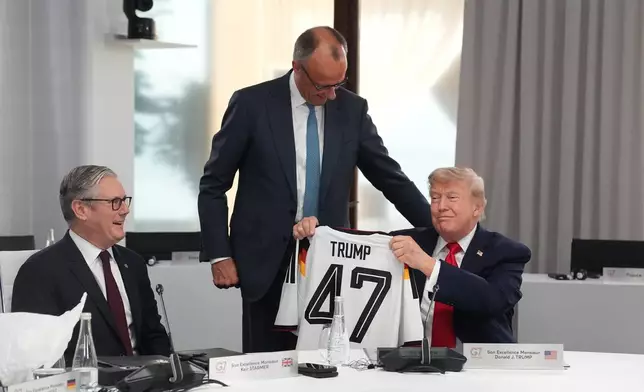 U.S. President Donald Trump, right, holds up a jersey with the number 47 on it as British Prime Minister Keir Starmer, left, and German Chancellor Friedrich Merz look on during a working session at the G7 summit in Evian-les-Bains, France, Tuesday, June 16, 2026. (AP Photo/Thibault Camus, Pool)
