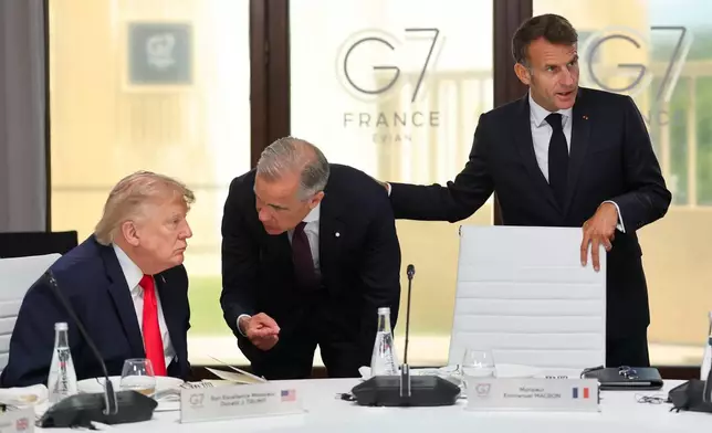French President Emmanuel Macron stands next to President Donald Trump, left, and Canadian Prime Minister Mark Carney, center, at a working lunch with leaders of G7 and the Middle East in Evian-les-Bains, France, Tuesday, June 16, 2026. (Christian Hartmann/Pool Photo via AP)