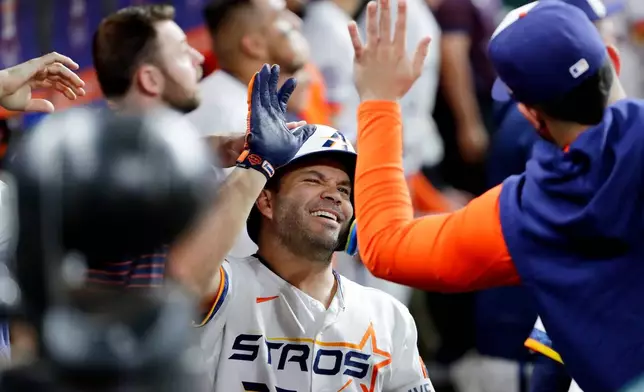 Houston Astros' Jose Altuve, center, collects high-fives in the dugout after his solo home run against the Detroit Tigers during the third inning of a baseball game Monday, June 15, 2026, in Houston. (AP Photo/Michael Wyke)
