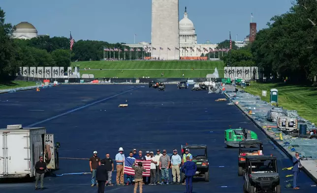 Interior Secretary Doug Burgum, center, poses for a photo with workers while touring the Lincoln Memorial Reflecting Pool after it was coated in a blue swimming pool surface ahead of the United States' 250th anniversary, Wednesday, June 3, 2026, in Washington. (AP Photo/Julia Demaree Nikhinson)