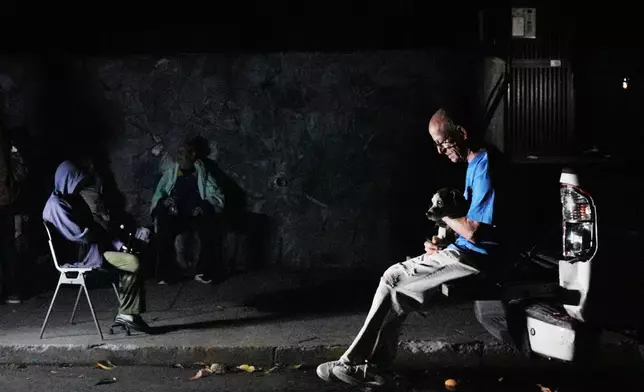 A man sits with his dog outside his home after an earthquake in Caracas, Venezuela, Wednesday, June 24, 2026. (AP Photo/Adrian Naranjo)