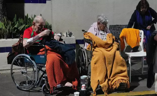 Seniors sit outside damaged buildings after an earthquake in Caracas, Venezuela, Wednesday, June 24, 2026. (AP Photo/Adrian Naranjo)