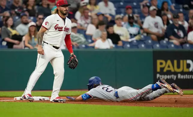 Texas Rangers' Cameron Cauley, right, slides into third base with a triple in front of Cleveland Guardians third baseman Gabriel Arias, left, in the seventh inning of a baseball game against the Cleveland Guardians in Cleveland, Monday, June 29, 2026. (AP Photo/Sue Ogrocki)