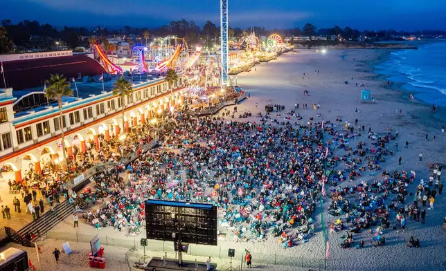 Fans watch a broadcast of the World Cup Group D soccer match between the United States and Turkey at the beach boardwalk in Santa Cruz, Calif., Thursday, June 25, 2026, (AP Photo/Noah Berger)