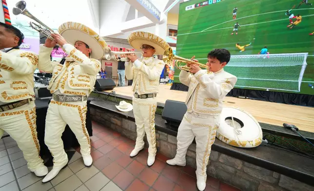 Members of the Mariachi Mexicanisimo de Fort Worth play a celebratory tune as a large screen shows a replay of Mexico's Julian Quinones scoring his side's first goal on South Africa during the opening match of the FIFA World Cup soccer tournament, Thursday, June 11, 2026, as supporters gathered for a watch party in Fort Worth, Texas. (AP Photo/Julio Cortez)