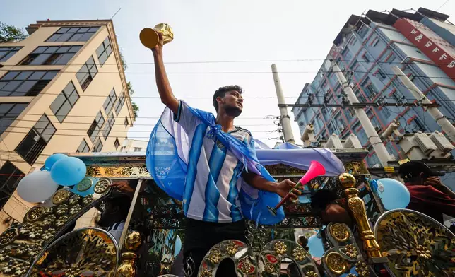 A Bangladeshi soccer fan wearing an Argentina jersey and holding a replica of the FIFA World Cup trophy in support of the team competing at the 2026 FIFA World Cup during a rally in Dhaka, Bangladesh, Tuesday, June 16, 2026. (AP Photo/Rajib Dhar)