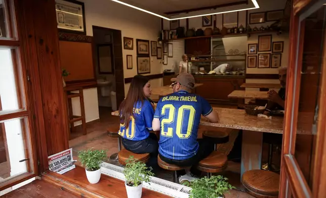 Bosnian national soccer team fans dressed in jerseys eat at a traditional restaurant, ahead of the soccer match of the FIFA World Cup 2026 between Switzerland and Bosnia, in Sarajevo, Bosnia, Thursday, June 18, 2026. (AP Photo/Armin Durgut)