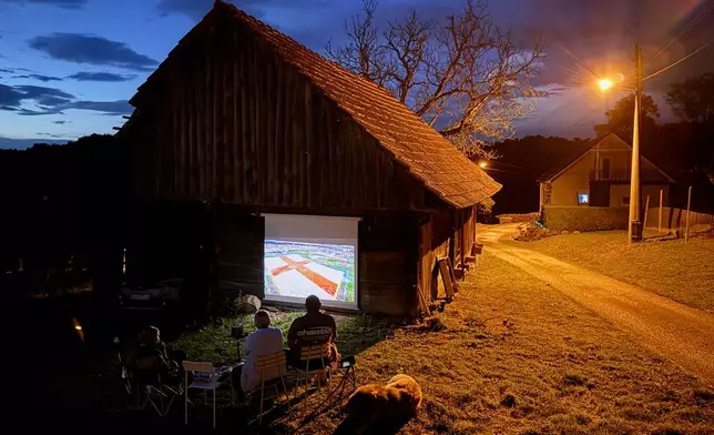 Locals watch the World Cup soccer match between England and Croatia projected on the barn wall, in Kumrovec, northern Croatia, Wednesday, June 17, 2026. (AP Photo/Darko Bandic)