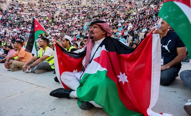 A Jordanian soccer fan wearing a traditional keffiyeh and draped in national flags watches the FIFA World Cup Group J match between Jordan and Argentina on a large screen at the Roman Amphitheater in downtown Amman, Jordan, early Sunday, June 28, 2026. (AP Photo/Raad Adayleh)