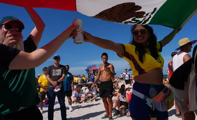 A group of fans use a Mexican flag for shade as they watch the opening World Cup Group A soccer match between Mexico and South Africa on beachfront big screens, in Miami Beach, Fla., Thursday, June 11, 2026. AP Photo/Rebecca Blackwell)