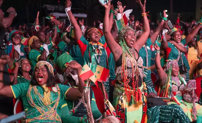 Members of a Senegal supporters group who were unable to obtain U.S. visas, celebrate after their team scores a goal during a World Cup soccer match against Iraq, at the Place de la Nation fan zone in Dakar, Senegal, Friday, June 26, 2026. (AP Photo/Sylvain Cherkaoui)