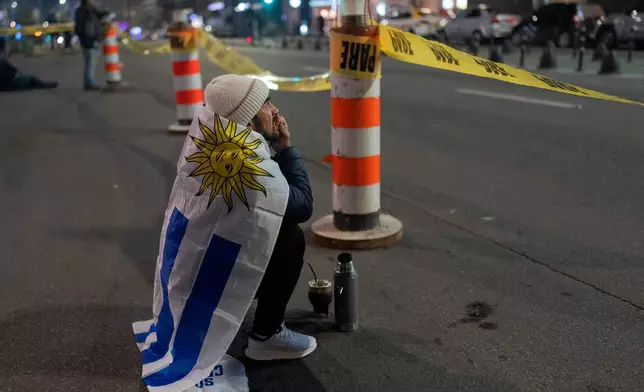 A soccer fan watches a broadcast of the World Cup soccer match between Uruguay and Cabo Verde in downtown Montevideo, Uruguay, Sunday, June 21, 2026. (AP Photo/Matilde Campodonico)