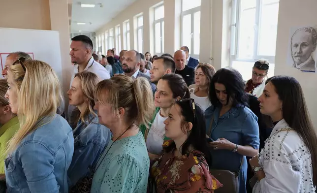 People wait in line at a polling station for an early parliamentary election, the third in 18 months, in the northern Serb-dominated part of ethnically divided town of Mitrovica, Kosovo, Sunday, June 7, 2026. (AP Photo/Dejan Simicevic)