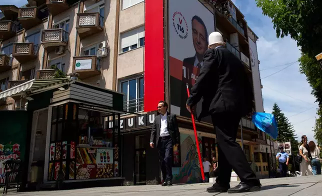 People pass by a giant election poster of acting prime minister Albin Kurti, in capital Pristina, Kosovo, Friday, June 5, 2026, ahead of snap parliamentary elections on June 7. (AP Photo/Visar Kryeziu)