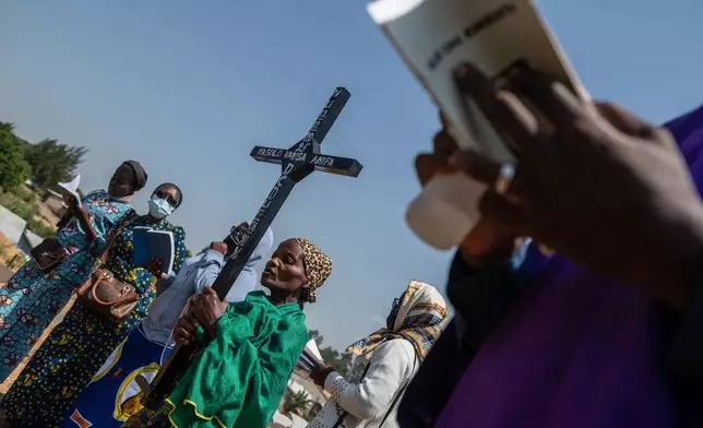 A woman holds a cross during a burial ceremony for Vanisa Anifa, a 6-month old orphaned girl who died of Ebolaat, in Bunia, Congo, Friday, June 19, 2026. (AP Photo/Moses Sawasawa)