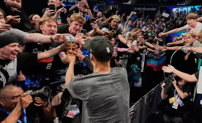 San Antonio Spurs forward Victor Wembanyama, center, walks over to Spurs fans as he holds his MVP trophy and celebrates after Game 7 of the Western Conference finals of the NBA basketball playoffs series win against the Oklahoma City Thunder, Saturday, May 30, 2026, in Oklahoma City. (AP Photo/Tony Gutierrez)