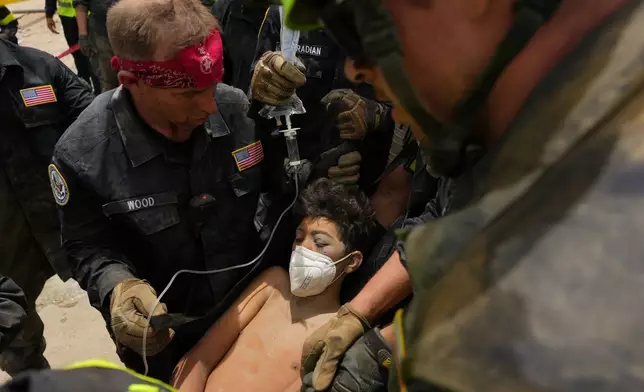 U.S. firefighters from the Fairfax County search and rescue team pull a boy from the rubble after rescuing him and his father from a building that collapsed in the earthquakes in La Guaira, Venezuela, Sunday, June 28, 2026. (AP Photo/Matias Delacroix)