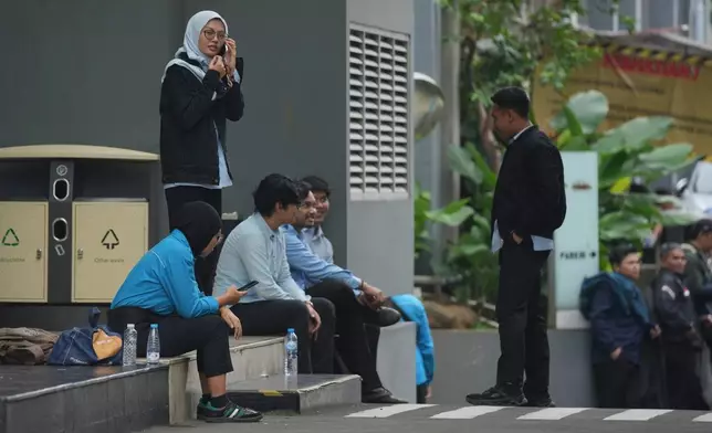 Employees wait outside the office of the National Nutrition Agency as it is being searched by prosecutors, in Jakarta, Indonesia, Wednesday, June 3, 2026. (AP Photo/Dita Alangkara)