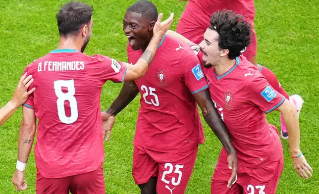 Portugal's Nuno Mendes (25) reacts with teammates Portugal's Bruno Fernandes (8) and Portugal's Vitinha (23) after scoring his team's second goal during the World Cup Group K soccer match between Portugal and Uzbekistan in Houston, Tuesday, June 23, 2026. (AP Photo/Karen Warren)