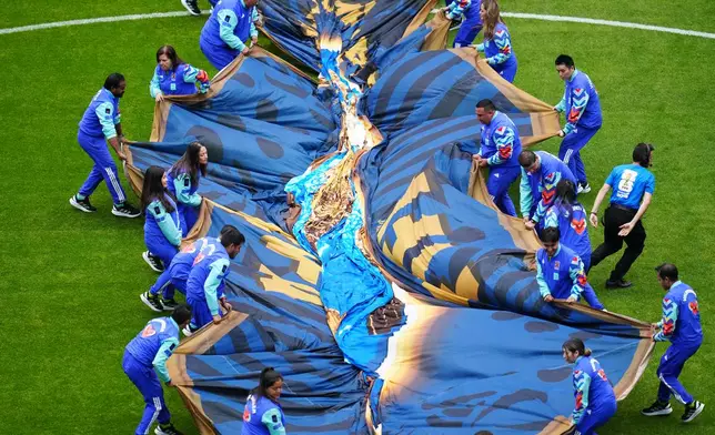 Volunteers put the FIFA logo on the pitch ahead of the World Cup Group K soccer match between Portugal and Uzbekistan in Houston, Tuesday, June 23, 2026. (AP Photo/Karen Warren)