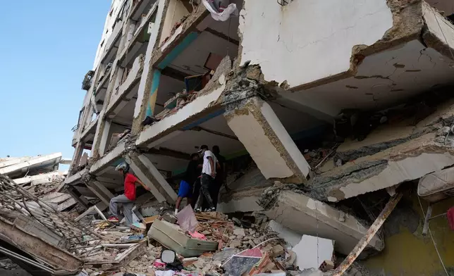 Residents walks through the rubble two days after earthquakes struck Catia La Mar, Venezuela, Friday, June 26, 2026. (AP Photo/Fernando Vergara)