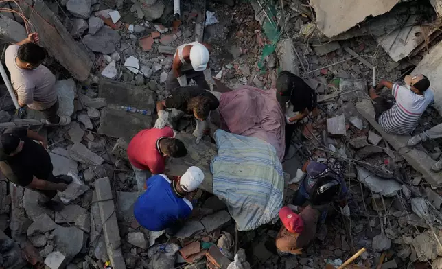 Residents pull a body from the rubble two days after earthquakes struck La Guaira, Venezuela, Friday, June 26, 2026. (AP Photo/Ariana Cubillos)