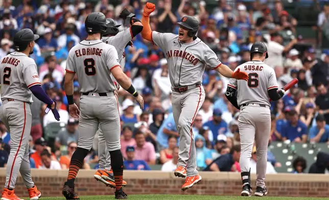 San Francisco Giants' Matt Chapman, center, celebrates hitting a grand slam with teammates Luis Arraez (1) hidden, Bryce Eldridge (8) and Willy Adames (2) during the fourth inning of a baseball game against the Chicago Cubs at Wrigley Field, Friday, June 5, 2026, in Chicago. (AP Photo/Geoff Stellfox)